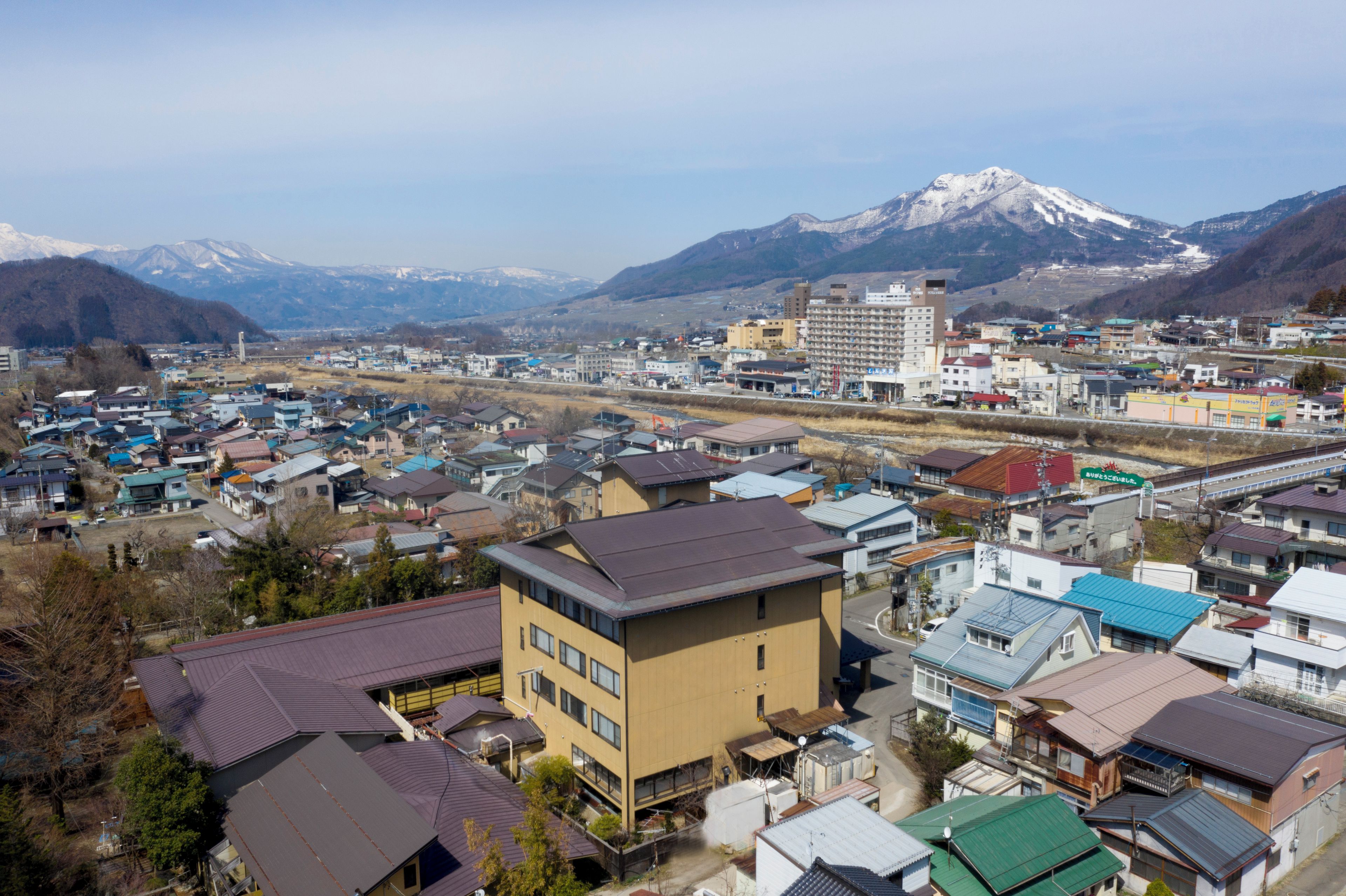 A town with a mix of residential and commercial buildings, a prominent hotel with a modern design, and a mountain in the background.
