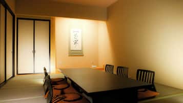 Una habitación tradicional japonesa con suelo de tatami, una mesa baja y sillas negras.