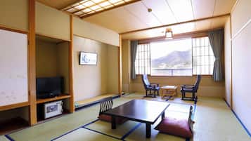 Une pièce de style japonais traditionnel, avec un sol recouvert de tatamis, une table basse et un téléviseur posé sur une étagère.