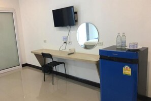 A room with a desk, a chair, a television mounted on the wall, a mirror, and a blue minibar. - Bankhun Residence (Nakhon Ratchasima)