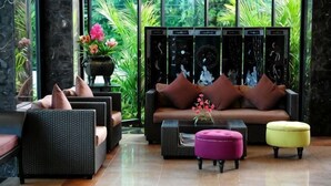 A modern living room with a sofa, armchairs, a coffee table, and an ottoman. - Bonito Chinos Hotel (Nakhon Sawan)