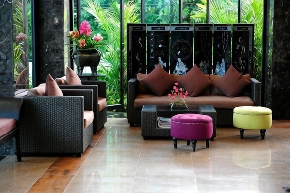Uma sala de estar moderna com sofá, poltronas, mesa de centro e um banquinho.