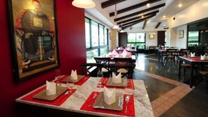 L’intérieur d’un restaurant, avec des tables dressées pour le service, une grande œuvre d’art encadrée accrochée au mur et une vue sur l’extérieur grâce à de grandes fenêtres.