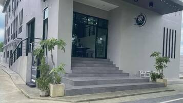 Un edificio moderno con una escalera que conduce a una entrada de vidrio, plantas en macetas y un logotipo en la pared.