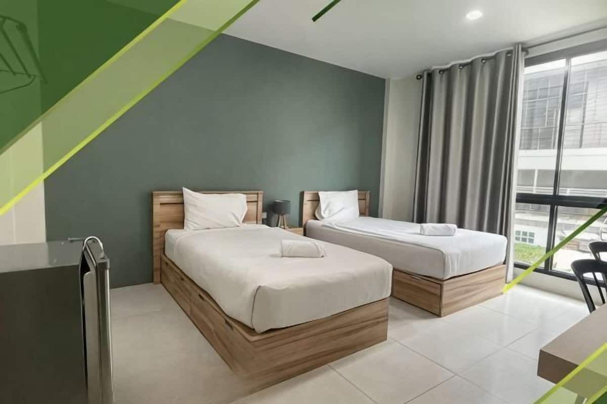 Habitación de hotel con dos camas, un escritorio y vistas a la ciudad.