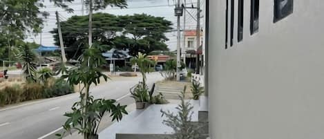 A building with a paved sidewalk, outdoor seating, and potted plants.