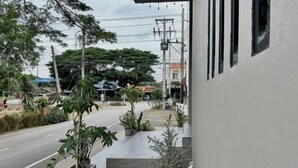 Um edifício com área externa coberta, plantas em vasos e uma cadeira branca.