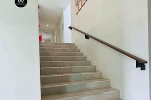 Una escalera con barandilla de madera y escalones color beige.