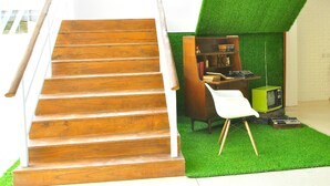 A staircase leading to a room with a green artificial grass floor, a wooden bookshelf, and a vintage green television. - Summer Bed and Breakfast Hotel (Banjarmasin)