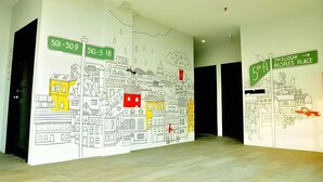 A hallway with a large mural of a cityscape, including street signs and buildings. - Summer Bed and Breakfast Hotel (Banjarmasin)