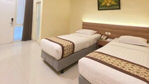 A hotel room with two beds, a painting on the wall, and a door with curtains. - Riverstone Hotel & Cottage (Batu)