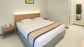 A hotel room with a bed, a nightstand, a framed picture on the wall, and an air conditioning unit. - Riverstone Hotel & Cottage (Batu)