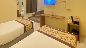 A hotel room with two beds, a TV, a desk with a computer, and a small trash bin. - Riverstone Hotel & Cottage (Batu)