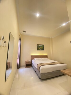 A hotel room with a bed, a nightstand, a mirror, and a painting on the wall.