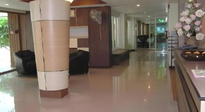 Un hall de hotel con mostrador de recepción, zona de estar y una planta decorativa.