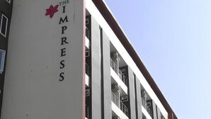 Un edificio con un letrero que dice 'THE IMPRESS' y un símbolo de flor roja.