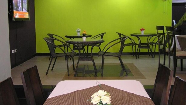 Un comedor con pared verde, televisor montado en la pared y ventilador de techo.