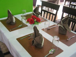 A dining table set with brown placemats, silverware, and clear glasses. - The Impress Khonkaen Hotel (Khon Kaen)