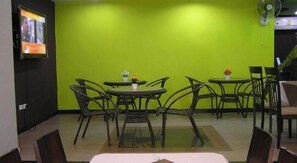 Un restaurant aux murs verts, avec de nombreuses tables et des chaises.