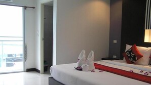 Una habitación de hotel con cama, mesita de noche, lámpara, ventana y puerta.