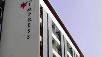 A building with a sign reading 'THE IMPRESS' and balconies with railings.
