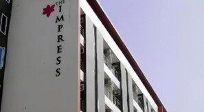 A building with a sign reading 'THE IMPRESS' and balconies with railings.