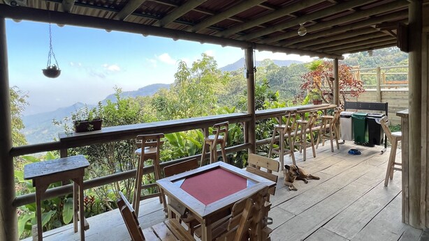 Una terraza de madera con una mesa y sillas, con vistas a un paisaje montañoso.