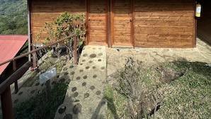 Un edificio de madera con techo rojo, una puerta de madera y un pequeño jardín con un sendero de piedra.