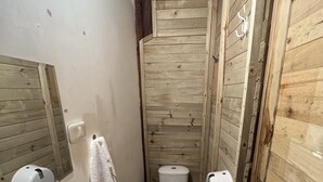 Un baño pequeño con paneles de madera, un lavabo, un inodoro y un espejo.