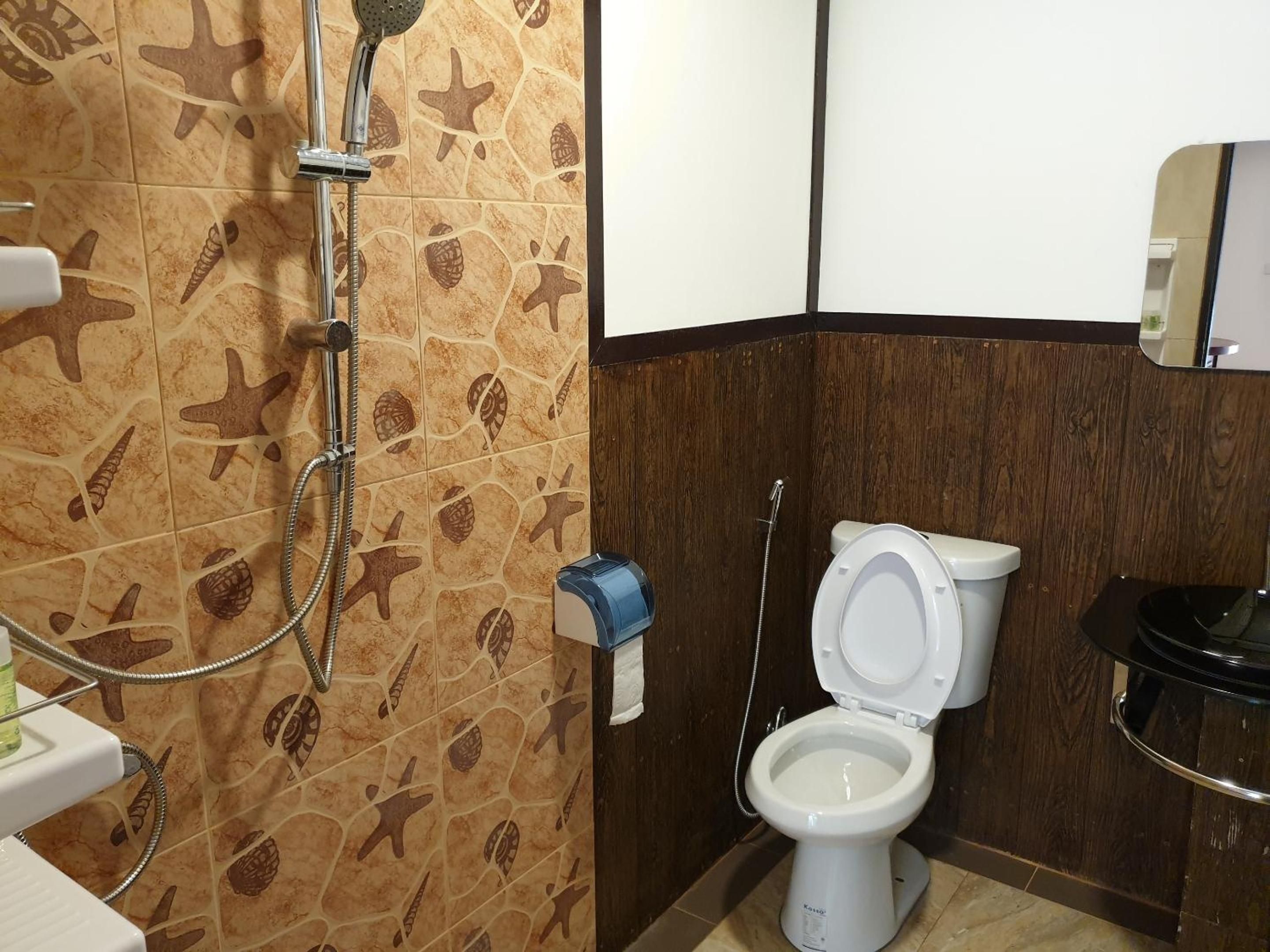 A bathroom with a shower, toilet, and a hand dryer.