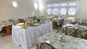 Un espace repas avec des tables dressées pour les convives, agrémenté de nappes à motifs floraux et de chaises.
