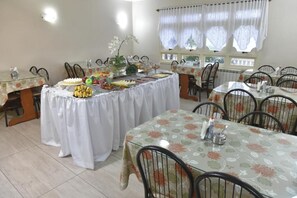 A dining area with tables set for guests, featuring floral tablecloths and chairs.