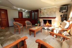 A living room with a fireplace, wooden furniture, and a television mounted on the wall.