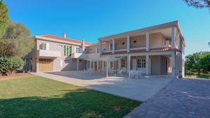 A two-story building with a covered patio area, outdoor seating, and a well-maintained lawn. - Maison Del Sole (Quartu Sant'Elena)
