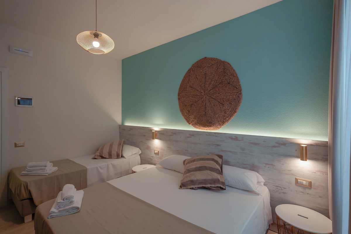 Habitación de hotel con dos camas, un tapiz redondo en la pared y una mesita redonda.