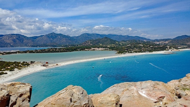A coastal landscape with a beach, clear blue waters, and distant mountains. - Maison Del Sole (Quartu Sant'Elena)