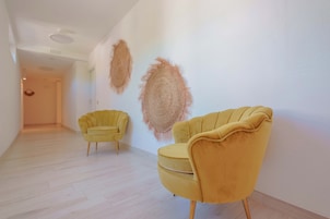 Un pasillo con dos sillones amarillos y una obra de arte con textura en la pared.
