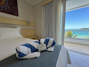 Een hotelkamer met een bed, een raam met uitzicht op zee en een handdoek op het bed.