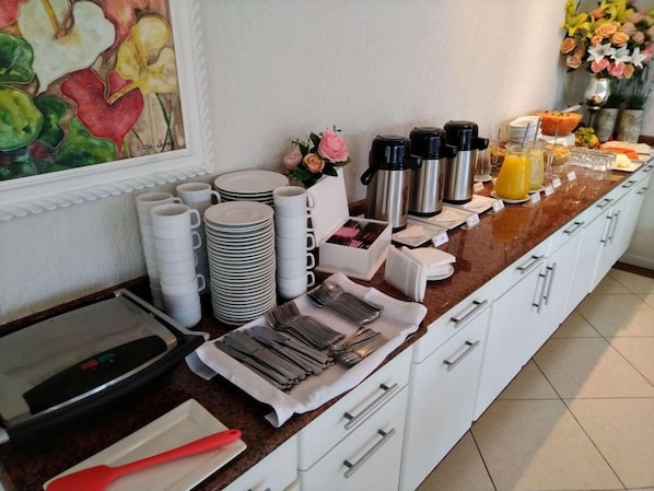 A breakfast buffet setup with coffee makers, juice, and a variety of dishes.