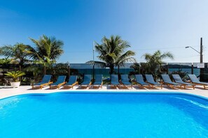 A swimming pool with lounge chairs and palm trees.