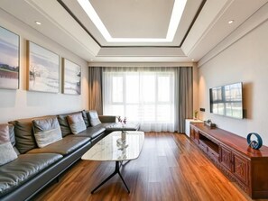 Un salon moderne avec un canapé d’angle, une table basse en verre et un meuble en bois.