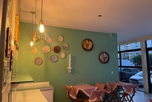Un coin repas agrémenté d’un mur vert, de différentes assiettes, d’une bougie blanche et d’une table recouverte d’une nappe à carreaux.