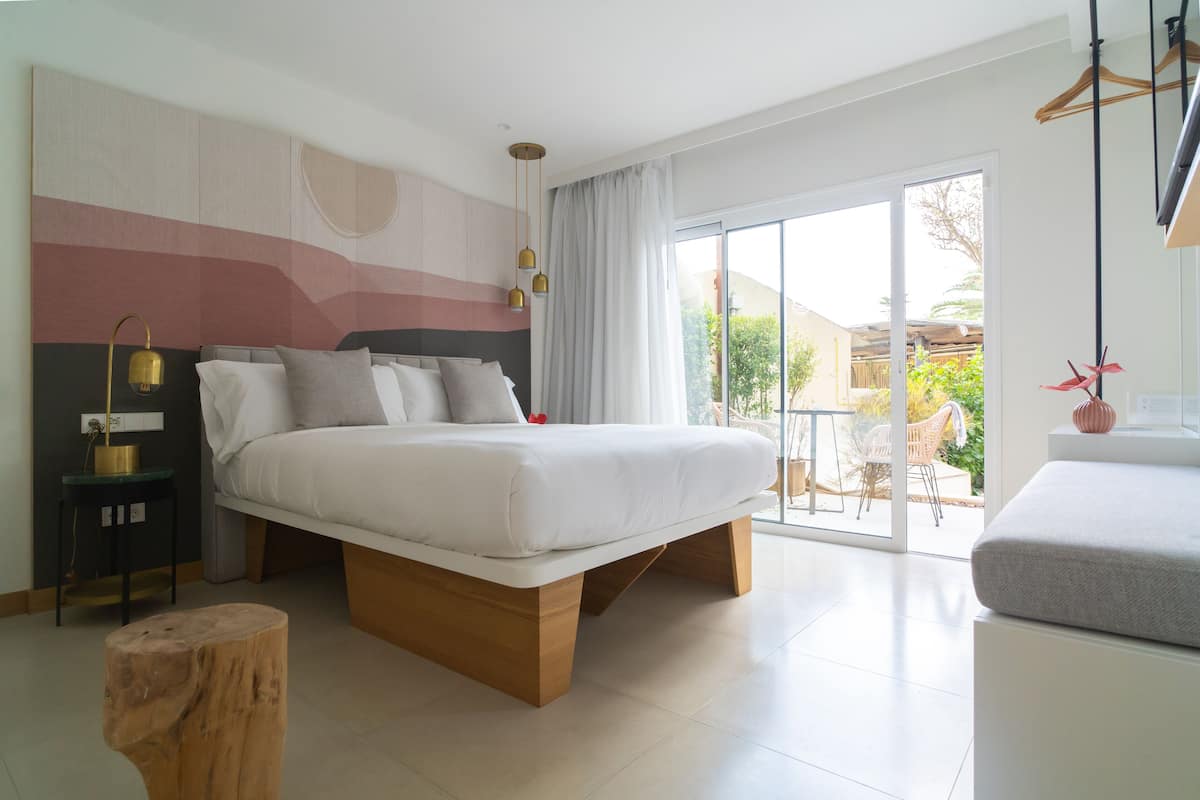 Ein modernes Schlafzimmer mit einem großen Bett, einem kleinen Tisch und Blick ins Freie.