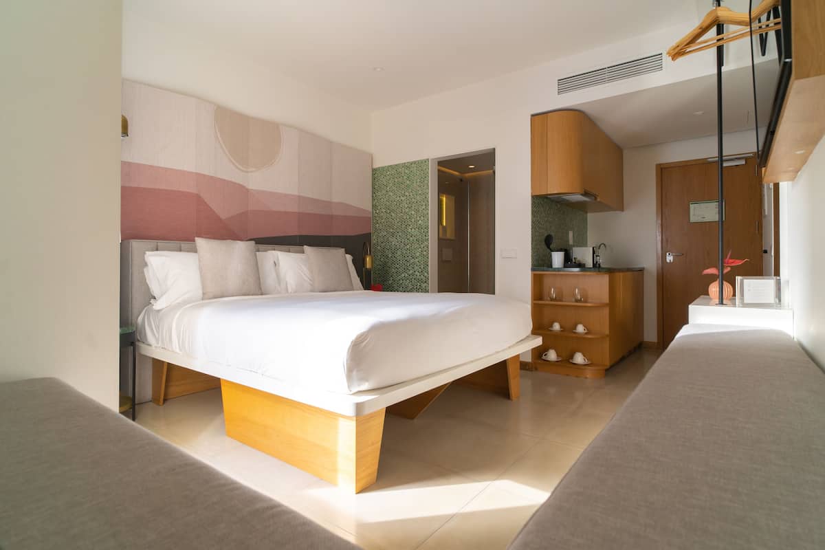 Ein modernes Schlafzimmer mit einem großen Bett, einem eingebauten Kleiderschrank und einer Küchenzeile.