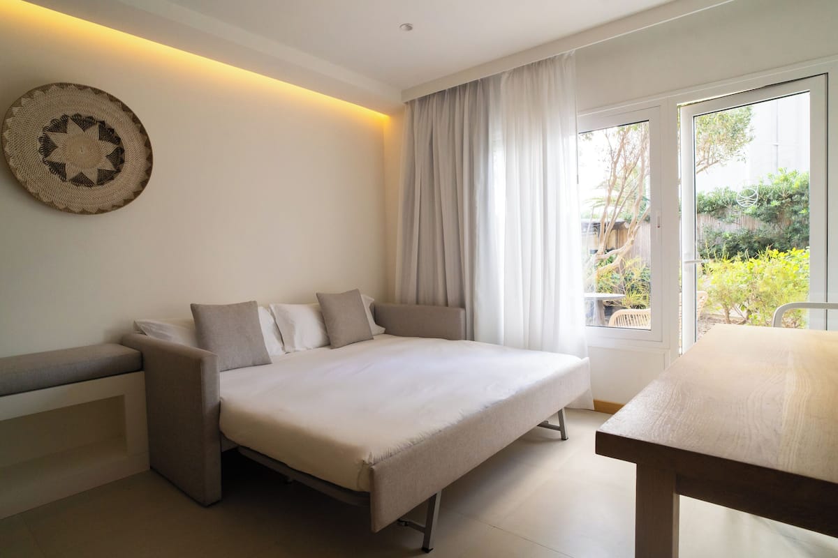 Ein modernes Schlafzimmer mit Schlafsofa, Esstisch und Blick ins Freie.