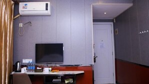 A hotel room with a flat-screen TV, a desk with a coffee maker, water bottles, and a small table. - Shell Shanghai Jiading District Tongji University Xinhuang Road Hotel (Shanghai)