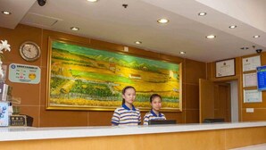 A reception desk with a large landscape painting above it, a clock, and various certificates on the wall. - 7 Days Premium (Shenzhen)
