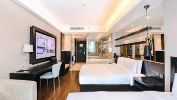 A hotel room with two beds, a desk, a TV, and a mirror.