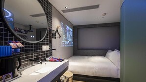 A modern hotel room with a large bed, a round mirror, a built-in TV, and a small kitchenette. - Fenk Attitude Hotel (Guangzhou)