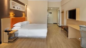 A hotel room with a bed, bedside table, TV, and a desk area. - 7 Days Premium·xiamen Airport (Xiamen)